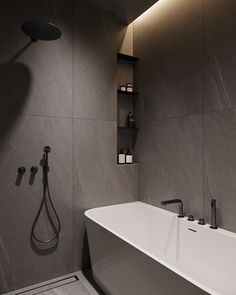 a bathroom with a bathtub, shower head and shelves on the wall next to it