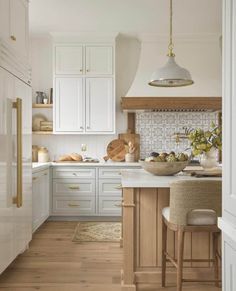 a kitchen with white cabinets and wood floors, an island countertop and two stools