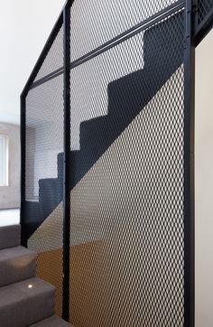 a stair case with metal mesh on the top and bottom, along with carpeted stairs