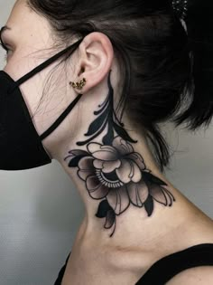 a woman's neck with a flower tattoo on it