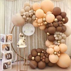 a large balloon arch with gold and white balloons on it, next to a cake