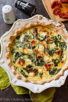 a quiche with spinach and cheese in a white dish