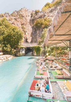 people sitting at tables on the side of a river