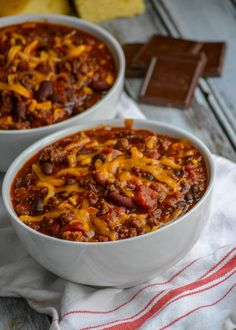 two white bowls filled with chili and cheese