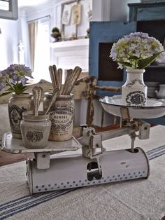 an old scale with flowers and spices on it sitting on a table in front of a fireplace