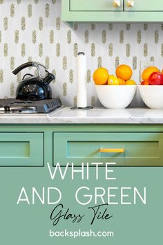 white and green kitchen cabinets with bowls of fruit on the counter, in front of an electric tea kettle