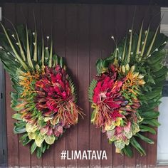 two wreaths made out of leaves and flowers on the side of a wooden door