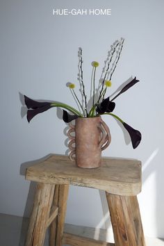 a vase filled with flowers sitting on top of a wooden stool