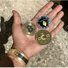 a person's hand holding three different types of bitcoins in their palm