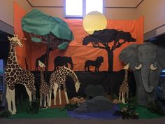 an elephant, giraffes and other animals are displayed in front of a backdrop