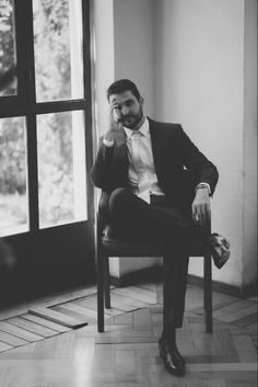 a man sitting in a chair talking on a cell phone while wearing a suit and tie