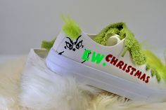 a pair of white shoes with green fur around them on top of a furry surface