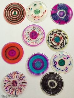 six different colored plates are arranged in a circle on a white surface with black, red, blue, and green designs