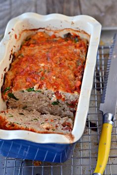 a casserole dish with meat and sauce in it on a cooling rack next to a knife