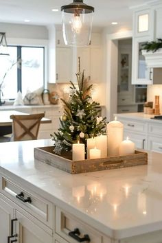 a christmas tree is sitting on top of a kitchen counter with candles in front of it