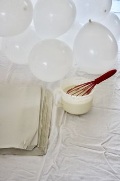 some balloons are floating in the air near a bowl with whisk on it