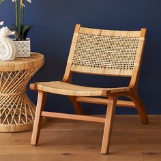 a wicker chair next to a small table with flowers on it and a vase