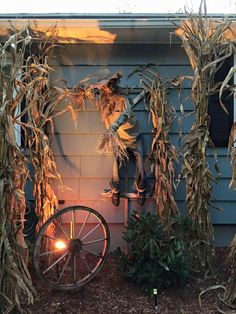 an old wagon is sitting in front of a house decorated with corn stalks and scarecrows