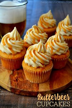 cupcakes with frosting on a wooden board next to a glass of beer