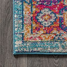 a multicolored area rug on top of a wooden floor next to a gray wall