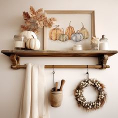 a shelf filled with pumpkins, candles and other fall decor on top of a wall