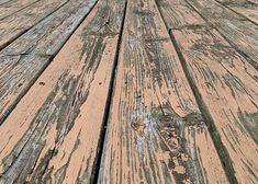 an old wooden floor with peeling paint and chipped wood planks in the middle