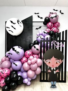 there are balloons and bats on the wall in this halloween themed room, with a girl standing next to it