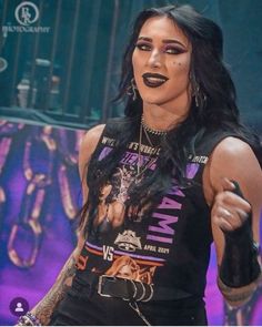 a woman with black makeup and piercings on her face is standing in front of a stage