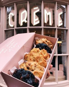 a person holding up a box of cookies in front of a store window with the words creme written on it