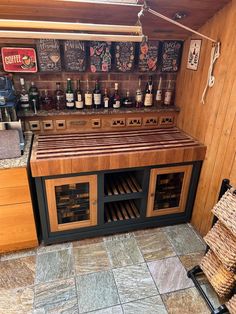 a wooden counter top sitting inside of a kitchen next to a wall filled with bottles