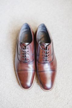 a pair of brown shoes sitting on top of a white carpet