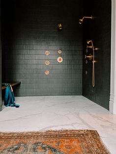 a black tiled shower with gold fixtures and rug