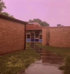 a brick building with grass and water on the ground