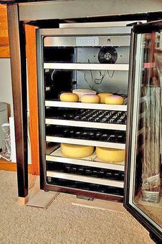 an open refrigerator filled with lots of cheeses on top of a carpeted floor