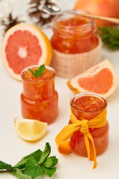 two jars filled with jam next to sliced grapefruit