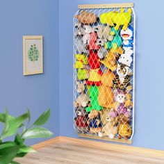 a bunch of stuffed animals in a cage on the wall next to a potted plant