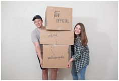 two people standing next to each other with boxes on their heads and one person holding the box