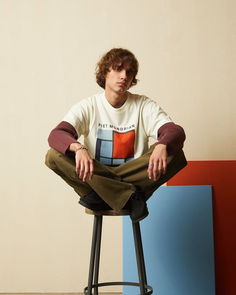 a young man sitting on top of a stool