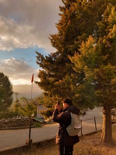 two people standing next to each other near trees