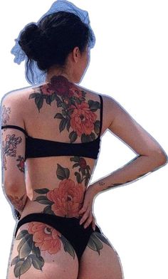 a woman with tattoos on her back standing next to the ocean