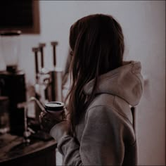 a woman standing in front of a counter holding a coffee cup and looking into the distance