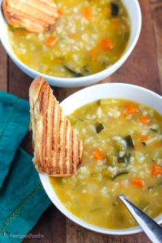 two bowls of soup with bread on the side