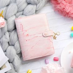 a pink and white marbled notebook sitting on top of a blanket next to candy