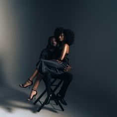 a woman sitting on top of a chair next to a man in a black dress