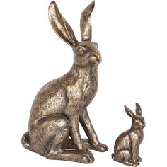 two bronze rabbits sitting next to each other on a white background and one is looking at the camera