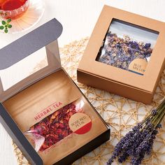 an open box with dried flowers inside on a doily next to a cup and saucer