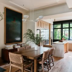 a dining room table with wicker chairs and a large painting hanging on the wall