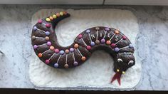 a cake shaped like a snake with chocolate icing and sprinkles on it