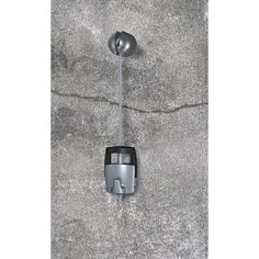 a parking meter attached to the side of a concrete wall next to a street light