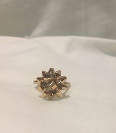 a gold ring with spikes on it sitting on a white cloth